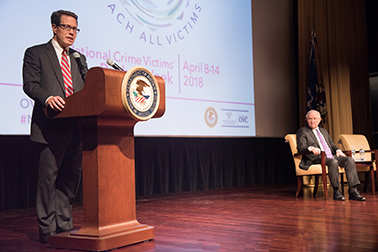 Principal Deputy Assistant Attorney General for the Office of Justice Programs Alan Hanson speaks at the 2018 National Crime Victims' Service Awards Ceremony as U.S. Attorney General Jeff Sessions looks on.