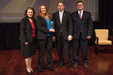 Eva Velasquez receives the 2019 National Crime Victim Service Award with (from left) OVC Director Darlene Hutchinson, Deputy Attorney General Rod J. Rosenstein, and Principal Deputy Assistant Attorney General for the Office of Justice Programs Matt M. Dummermuth.