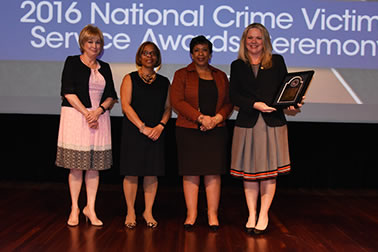 Staff from the National Domestic Violence Hotline accepts the Award for Professional Innovation in Victim Services. Katie Ray-Jones from the National Domestic Violence Hotline accepts the award with (from left) Joye E. Frost, Director, Office for Victims of Crime; Karol V. Mason, Assistant Attorney General, and Attorney General Loretta E. Lynch.