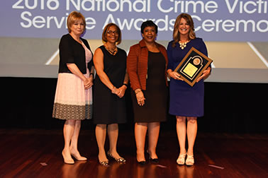 National Crime Victim Service Award recipient Kim Case with (from left) Joye E. Frost, Director, Office for Victims of Crime; Karol V. Mason, Assistant Attorney General; and Attorney General Loretta E. Lynch.