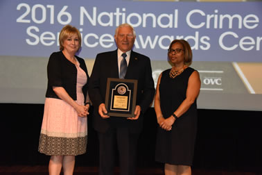 National Crime Victims’ Service Award recipient Dr. John P.J. Dussich accepts the award with (from left) Joye E. Frost, Director, Office for Victims of Crime and Karol V. Mason, Assistant Attorney General.