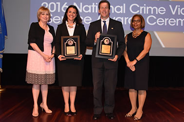 Stephen J. Pfleger and Laura Day Rottenborn accept the Crime Victims Financial Restoration Award with (from left) Joye E. Frost, Director, Office for Victims of Crime and Karol V. Mason, Assistant Attorney General.